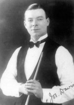 A black and white photograph of a man with Brylcreemed black hair, white shirt, black waistcoat, and black bow tie, holding a snooker cue in front of him; his autograph is visible in bottom right corner of photo