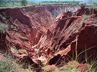 A vast, red soil gully caused by erosion