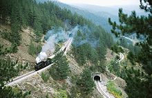 Steam passenger train on a winding, mountainous switchback