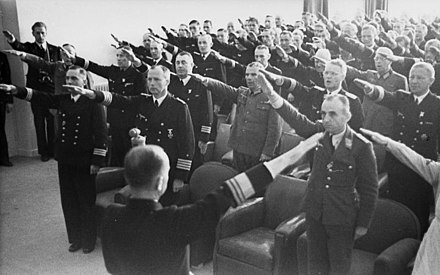 Black and white photograph of men wearing military uniforms with their right arms outstretched