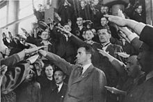 Black and white photograph of a group of men wearing business suits raising their right arms in a Nazi salute