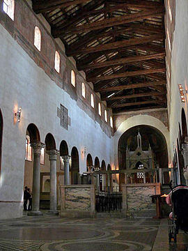 The interior of a narrow and rather dark church that has columns down each side supporting a plain wall with small high windows.