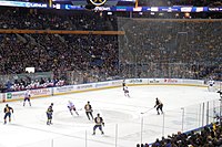 View of an ice hockey rink and game in front of a large crowd in an arena