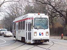 A white single-car trolley in street running.