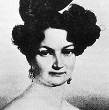 A young woman with black hair pinned up looking sternly
