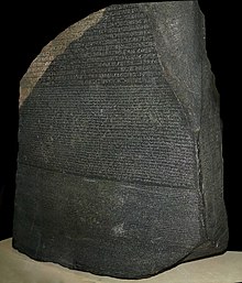 "A large dark grey-coloured slab of stone with text that uses Ancient Egyptian hieroglyphs, demotic and Greek script in three separate horizontal registers"