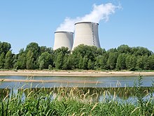 Nuclear power plant in Cattenom, France four large cooling towers expelling white water vapor against a blue sky