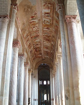A tall narrow church interior with rounds columns in delicate pastel colours that rise without interruption from floor to vault.