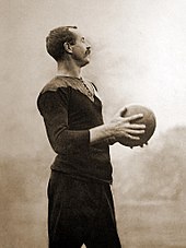 Image of Gallaher wearing his black rugby uniform and clasping a football.