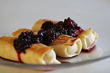 picture of three cheese blintzes with blackberries and sauce on top