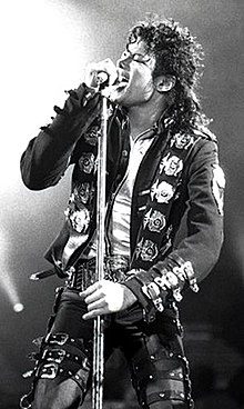 Una fotografía de Michael Jackson cantando en un micrófono.