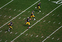 Four players run up the field as the kicker executes a kickoff