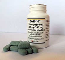 A white prescription bottle with the label Stribild. Next to it are ten green oblong pills with the marking 1 on one side and GSI on the other.