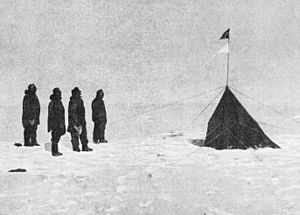 En un paisaje helado, cuatro figuras están de pie, a la izquierda, frente a una pequeña tienda puntiaguda desde la que ondean dos banderas triangulares.