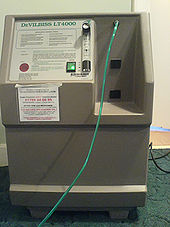 A gray device with a label DeVILBISS LT4000 and some text on the front panel. A green plastic pipe is running from the device.