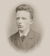 Head shot photo of a young man, similar in appearance to his brother, but neat, well-groomed and calm.