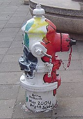 A painted hydrant with vertical stripes of multiple colors