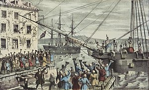 Two ships in a harbor, one in the distance. On board, men stripped to the waist and wearing feathers in their hair throw crates of tea overboard. A large crowd, mostly men, stands on the dock, waving hats and cheering. A few people wave their hats from windows in a nearby building.