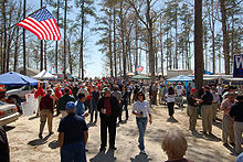 People stroll in a wooded area decorated with American flags.