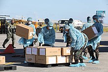 Workers unloading boxes of medical supplies at Villamor Air Base