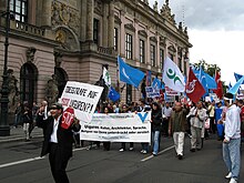 Street demonstration with banners, passing an official building