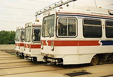 Three abreast white trolleys with a red stripe around the vehicle ends.