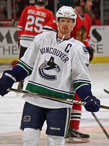 Un jugador de hockey sobre hielo con camiseta blanca y azul con el logo de una orca estilizada en forma de 