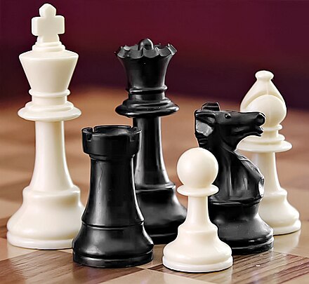 Uma seleção de peças de xadrez preto e branco em uma superfície quadriculada.