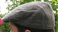A grey wool flat cap on a man's head.