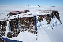 Photograph of a base near the edge of a barren cliff, surrounded by snow