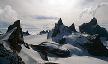Photograph of a barren mountainscape, with snow surrounding black peaks