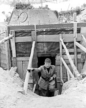 Mussolini climbing steps out of a bunker