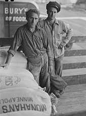 Two men who loaded flour and a bag of flour that says Monahan's Minneapolis and a Pillsbury truck