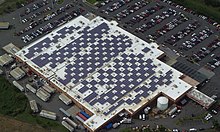 Aerial view of dozens of solar panels distributed around the roof of a Walmart store