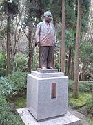 full-body statue of man in double-breasted suit on tall granite base