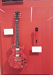 A photograph of Swift's decorated red Les Paul guitar and cordless microphone