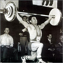 A man completing his weightlifting routine wearing one-piece costume and weightlifting shoes