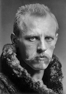 Retrato de cabeza y hombros de Fridtjof Nansen, mirando hacia la mitad derecha.  Tiene el pelo muy corto, un bigote amplio y claro y lleva un abrigo de piel grueso.