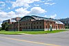 A large brick building with a rounded roof in back and flagpole in front.