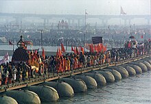Large group of people and vehicles crossing a pontoon bridge
