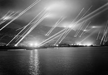 The Rock of Gibraltar, seen from the west, with at least 23 searchlights sending beams of light up into the night sky