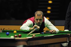 Photograph of Barry Hawkins with a cue and a rest.
