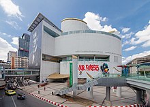 A modern-looking building with a smooth curved exterior on the corner of a road junction with several paintings on the wall