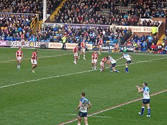 Two rugby league teams playing in front of full stands.