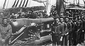 A group of twenty-six sailors posing around a rifled naval cannon