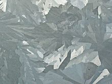 Merged elongated crystals of various shades of gray.
