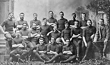 Photo of team players and management all of whom are seated or standing, in three rows, wearing their playing uniform and caps.