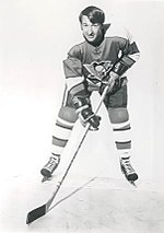Photograph of Lowell MacDonald holding his hockey stick on the ice