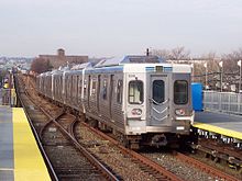 A silver subway train leaving a station.