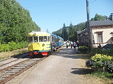 Blue-and-yellow railbus at a rural station